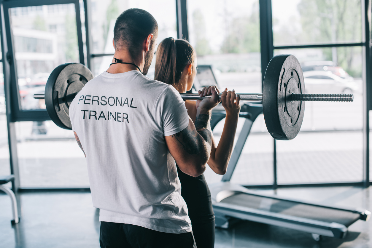 a persoanl trainer helping an athlete to progress with weight training